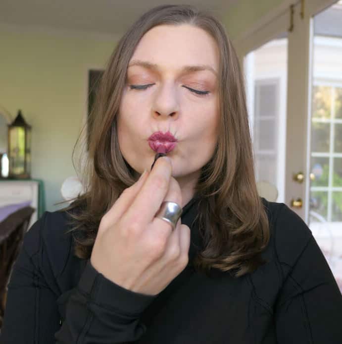 Putting on a Beautycounter mini color intense lipstick. 