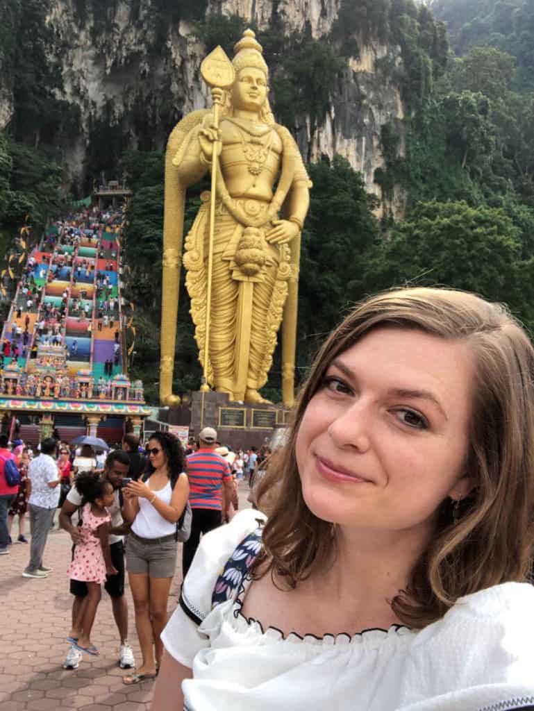 A woman taking a picture with a statue on the background