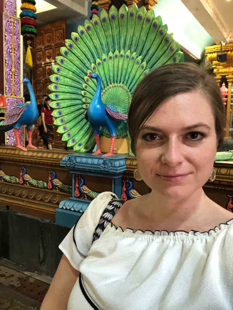 An image of a woman with a peacock statue.